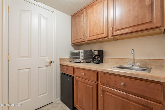 kitchen with sink, a textured ceiling, and light tile patterned floors