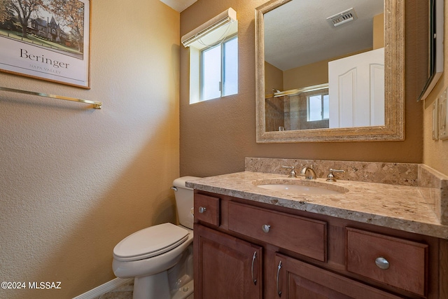 bathroom with toilet, vanity, and a shower with shower door