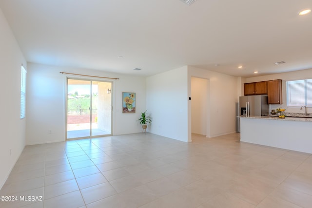 unfurnished living room featuring light tile patterned flooring and sink