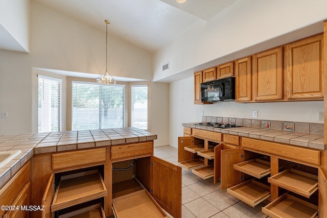 kitchen featuring stainless steel gas stovetop, hanging light fixtures, tile countertops, and light tile patterned floors