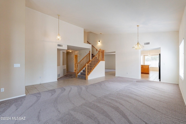 unfurnished living room with high vaulted ceiling and light carpet