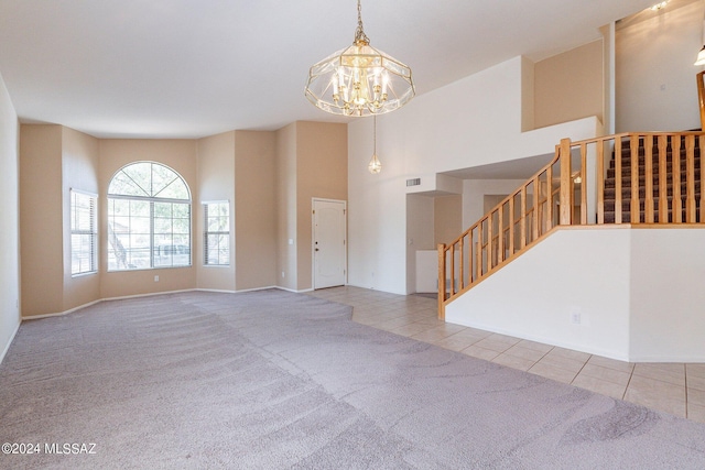 unfurnished living room with an inviting chandelier, light colored carpet, and a high ceiling