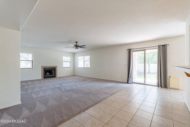 unfurnished living room featuring a fireplace, light colored carpet, ceiling fan, and plenty of natural light