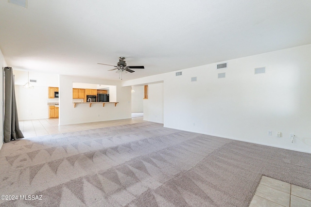 unfurnished living room featuring light colored carpet and ceiling fan