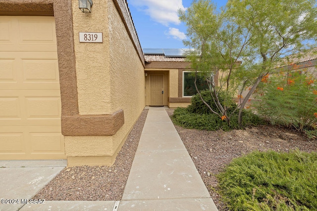 entrance to property with a garage and solar panels