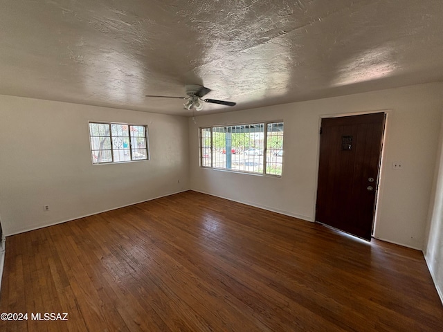 unfurnished room featuring a textured ceiling, dark hardwood / wood-style flooring, and ceiling fan