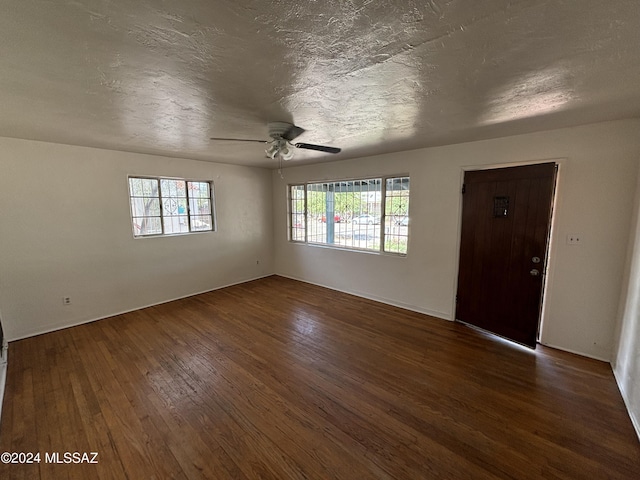 spare room with ceiling fan, dark wood-type flooring, and a textured ceiling