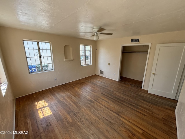 unfurnished bedroom with dark wood-type flooring, ceiling fan, and a textured ceiling