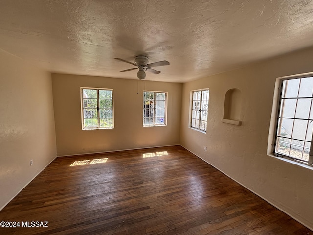 empty room with ceiling fan, dark wood-type flooring, and a textured ceiling