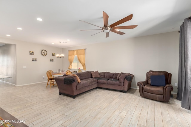 living room with ceiling fan with notable chandelier and light hardwood / wood-style floors