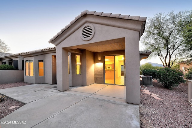 back house at dusk with a patio area and cooling unit