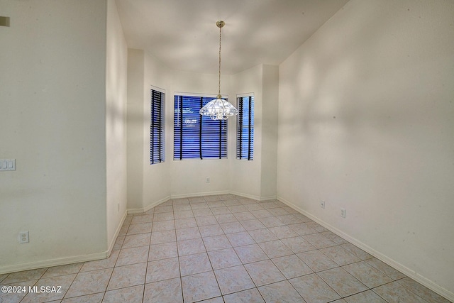 tiled spare room with a chandelier