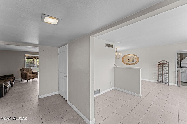 interior space featuring a chandelier, visible vents, a textured ceiling, and baseboards