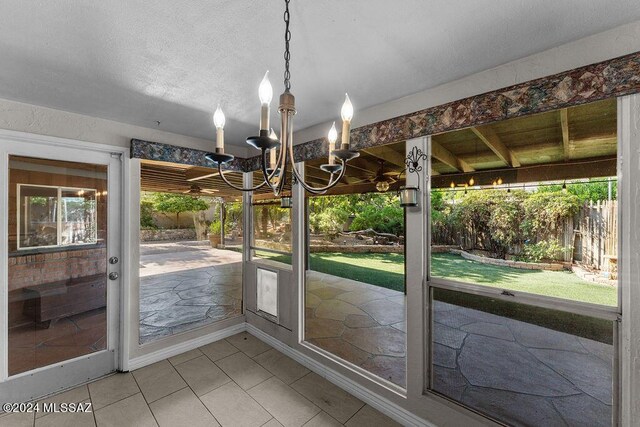 unfurnished sunroom featuring a healthy amount of sunlight and an inviting chandelier