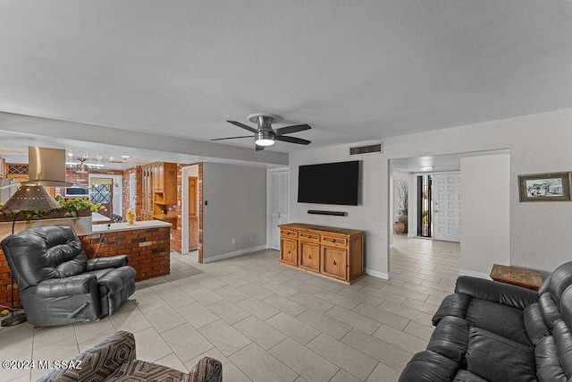 living area with ceiling fan, a textured ceiling, light tile patterned flooring, visible vents, and baseboards