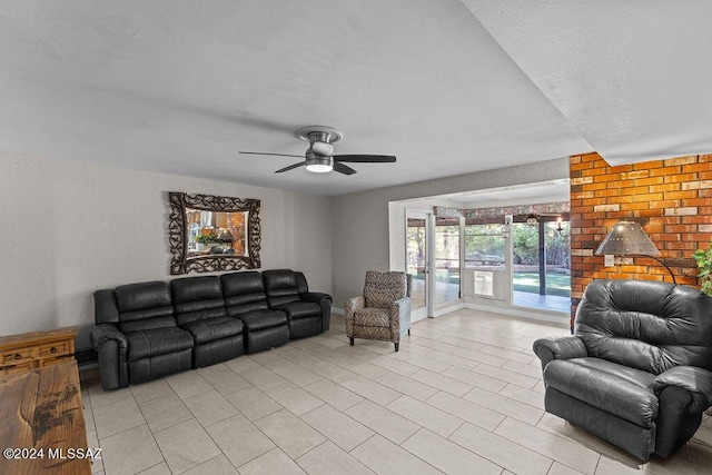 living room with light tile patterned floors, a textured wall, a textured ceiling, a ceiling fan, and baseboards