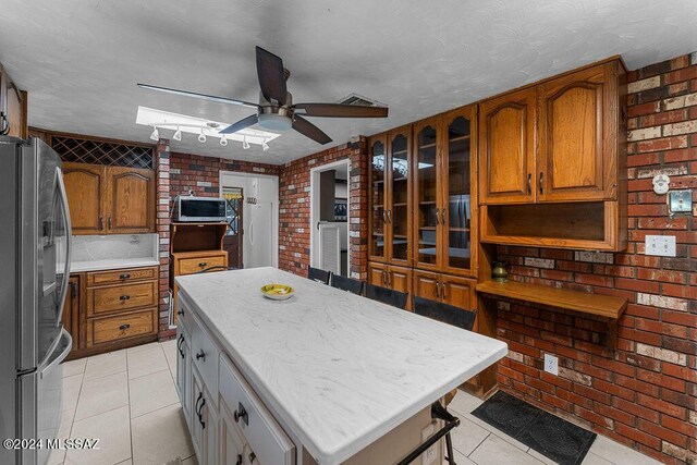 kitchen with stainless steel fridge, track lighting, a kitchen island, and ceiling fan