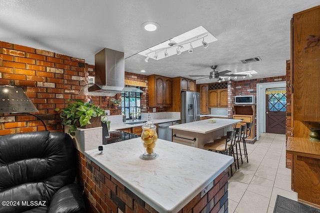 kitchen featuring a skylight, visible vents, light countertops, appliances with stainless steel finishes, and ventilation hood