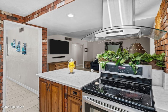 kitchen featuring brown cabinets, island exhaust hood, stainless steel electric stove, light countertops, and visible vents