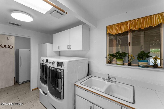 clothes washing area featuring light tile patterned flooring, independent washer and dryer, cabinets, and sink