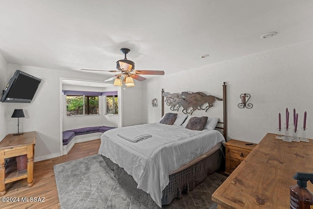 bedroom with wood finished floors, a ceiling fan, and baseboards