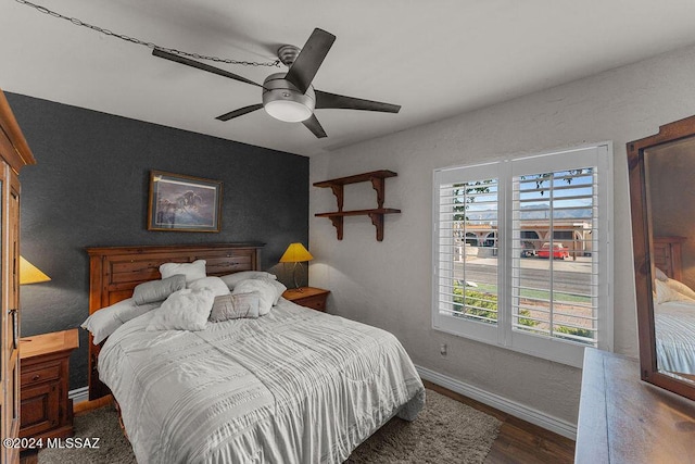 bedroom featuring a ceiling fan, a textured wall, baseboards, and wood finished floors