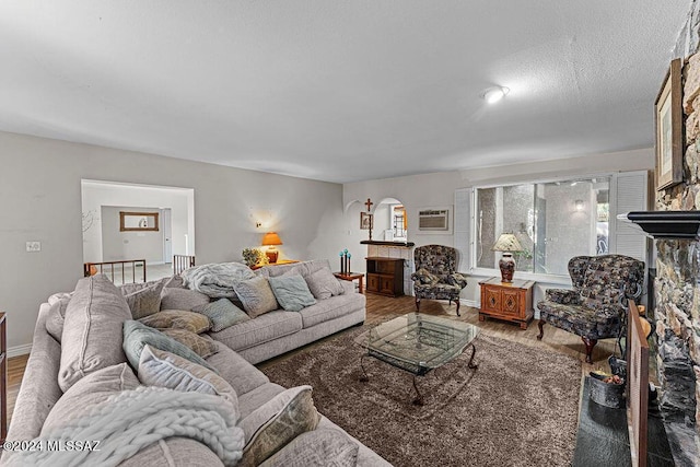 living area with a fireplace, a wall unit AC, wood finished floors, and baseboards