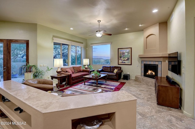 living room with a tiled fireplace and ceiling fan