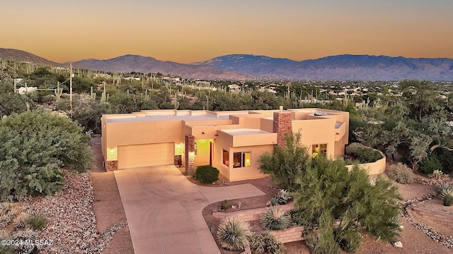 pueblo-style home featuring a garage and a mountain view