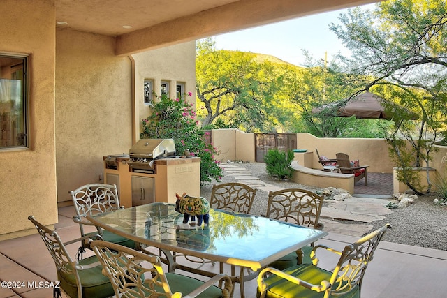 view of patio / terrace with grilling area, outdoor dining area, an outdoor kitchen, and fence