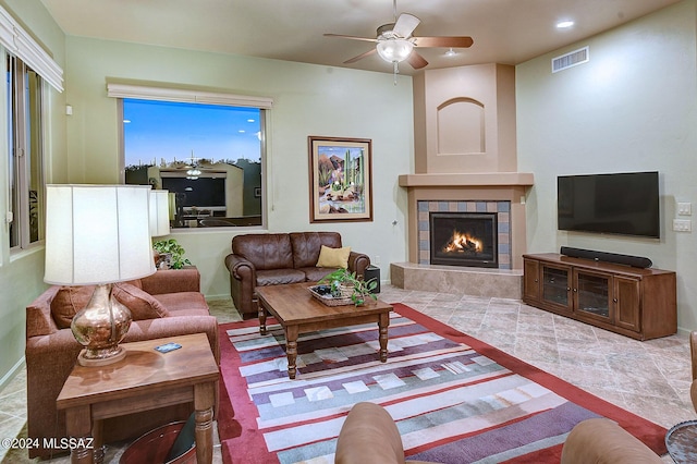 living room with ceiling fan and a tiled fireplace