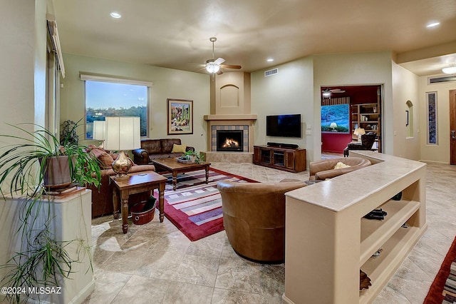 living room with a tile fireplace and ceiling fan