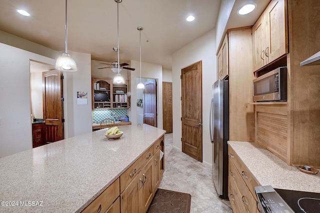 kitchen featuring light stone counters, decorative light fixtures, ceiling fan, stainless steel appliances, and backsplash