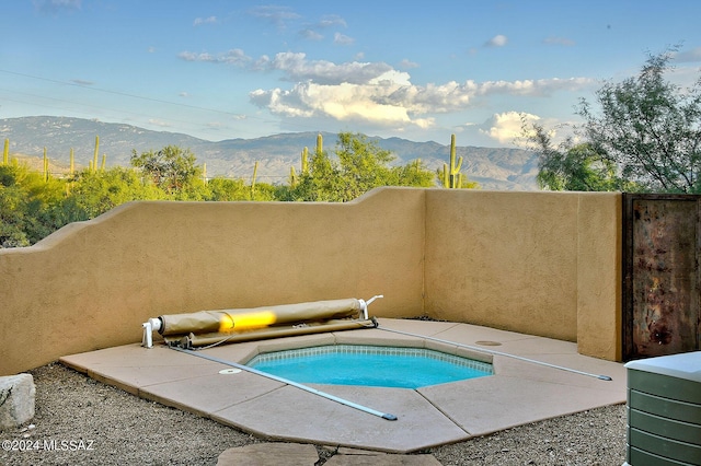 view of pool with a jacuzzi, a mountain view, and a patio