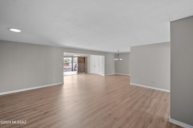 unfurnished living room with a notable chandelier and light hardwood / wood-style floors