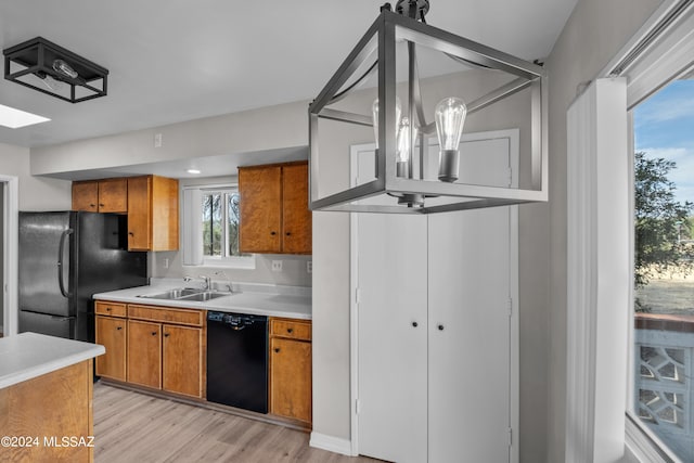 kitchen with sink, black appliances, hanging light fixtures, and light wood-type flooring