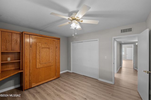 unfurnished bedroom featuring ceiling fan, light wood-type flooring, and a closet