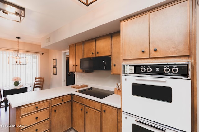 kitchen with kitchen peninsula, black appliances, hanging light fixtures, and a notable chandelier