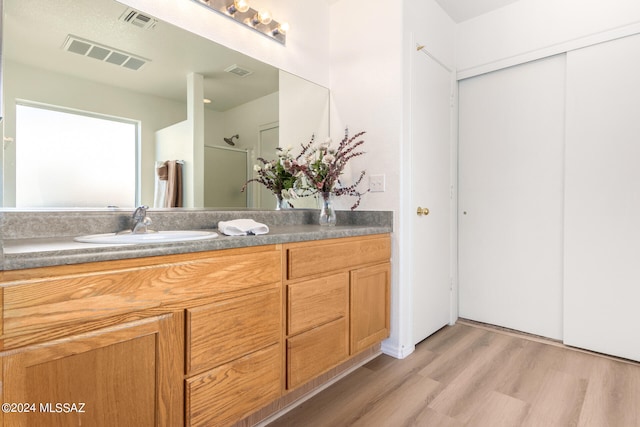 bathroom with walk in shower, vanity, and hardwood / wood-style floors