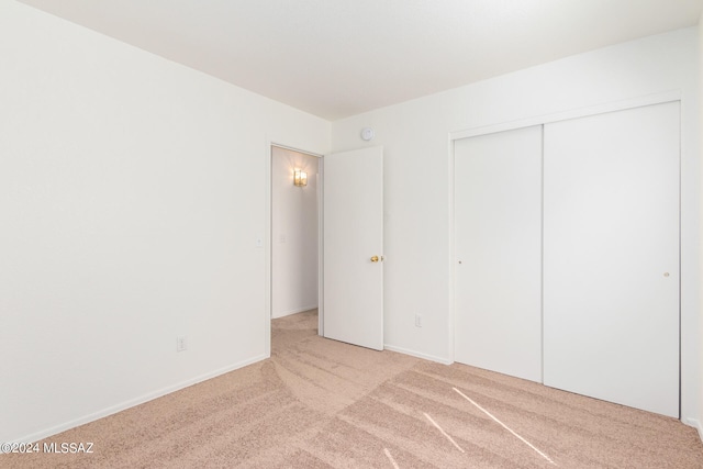 unfurnished bedroom with light carpet and a closet