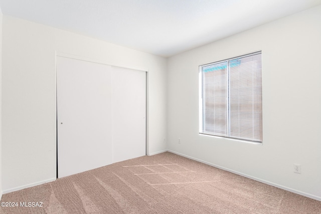 unfurnished bedroom with light carpet, a closet, and multiple windows