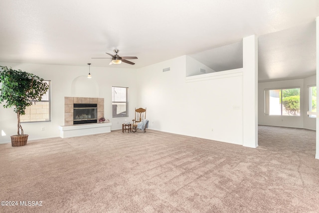 unfurnished living room with ceiling fan, a fireplace, vaulted ceiling, and carpet