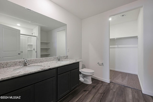 bathroom featuring wood-type flooring, walk in shower, vanity, and toilet