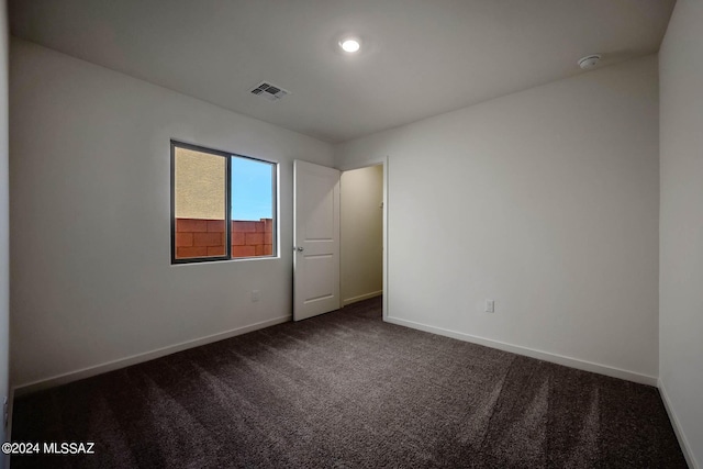 spare room with dark carpet