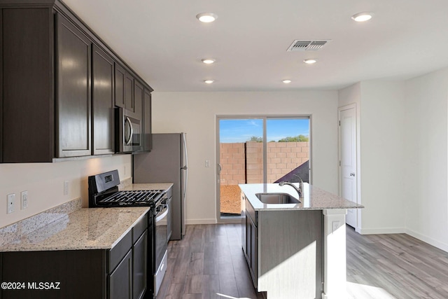 kitchen with light stone countertops, stainless steel appliances, hardwood / wood-style floors, and sink