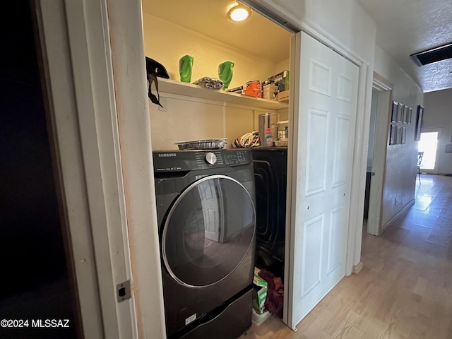 laundry room with washing machine and dryer and light hardwood / wood-style flooring