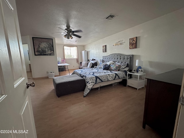 bedroom with hardwood / wood-style flooring, ceiling fan, and a textured ceiling