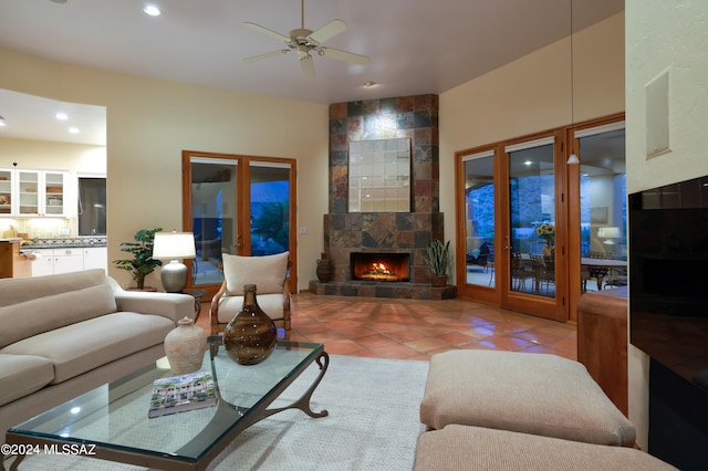 living room featuring a tile fireplace, french doors, light tile patterned floors, and ceiling fan