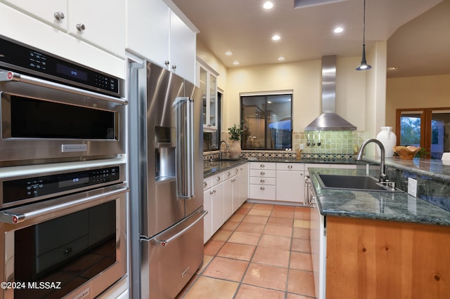 kitchen with white cabinetry, stainless steel appliances, wall chimney exhaust hood, and decorative light fixtures