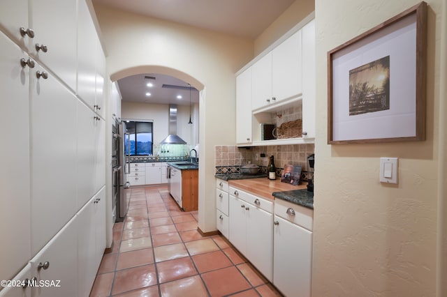 kitchen featuring white cabinets, sink, light tile patterned floors, and backsplash